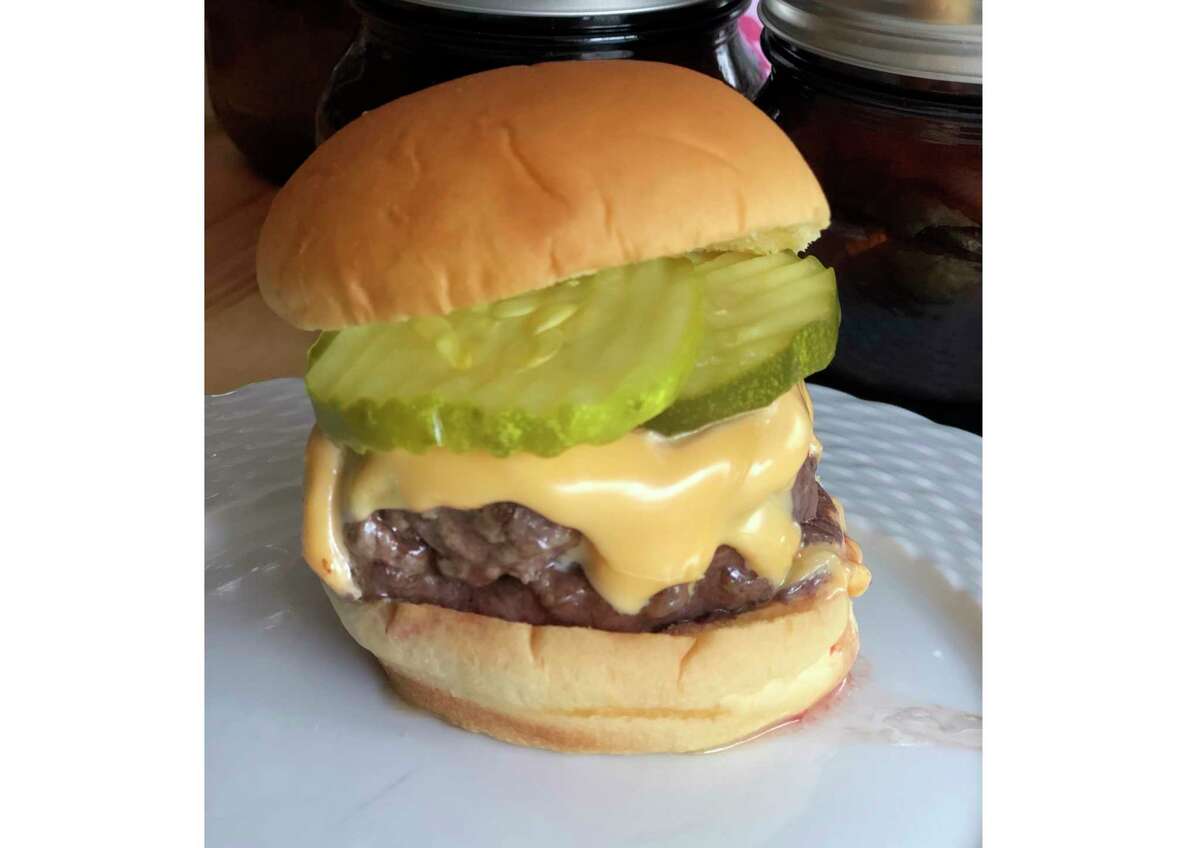 This June 2020 photo shows a cheeseburger topped with pickles in Alexandria, Va. To get the best tasting burger, try making your own blend with better quality cuts of beef. (Elizabeth Karmel via AP)