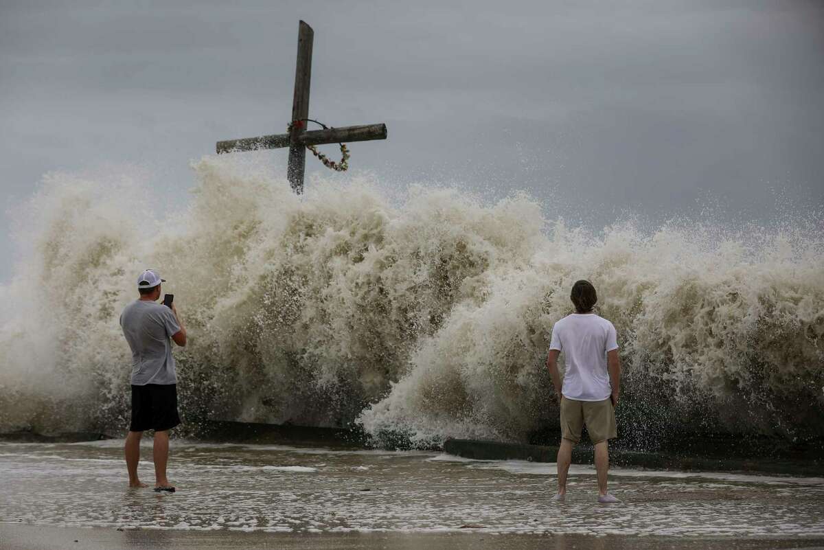 Mark Allums, left, and Hunter Clark watch waves crash ashore as outer bands from Hurricane Laura begin to hit the coast Wednesday, Aug. 26, 2020, in High Island. The two are from Bogata, Texas, near Paris, Texas, and they came to board up windows at a beach house in High Island.