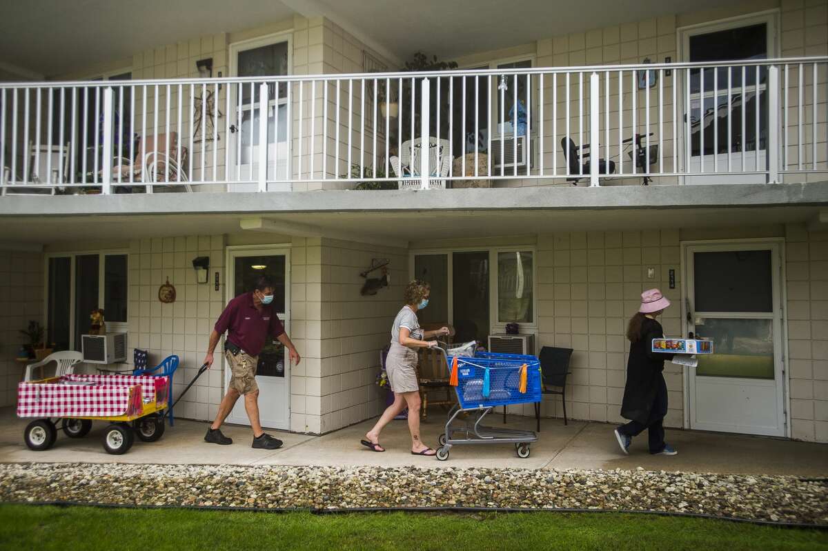 From left, Cleveland Manor staff members Perry Nunnari, Marilyn Rease and Alexandria Dodge deliver meals to residents during a picnic parade Wednesday, Aug. 26, 2020 at the apartment complex in Midland. The facility normally holds a more traditional annual picnic in the courtyard, but made adjustments this year due to COVID-19. (Katy Kildee/kkildee@mdn.net)