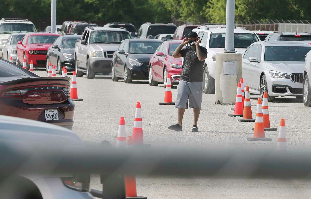 A man puts on a mask as lines of cars from evacuees of Hurricane Laura arrive at an emergency check-in site near Gembler and Paulson on Wednesday, Aug. 26, 2020. Hurricane Laura, categorized as a major hurricane, forced many from the Houston-Beaumont-Orange areas of Texas to vacate their homes and seek shelter in other cities such as San Antonio. Some arrived as early as Tuesday and many were in line again for additional housing vouchers to ride out the storm.