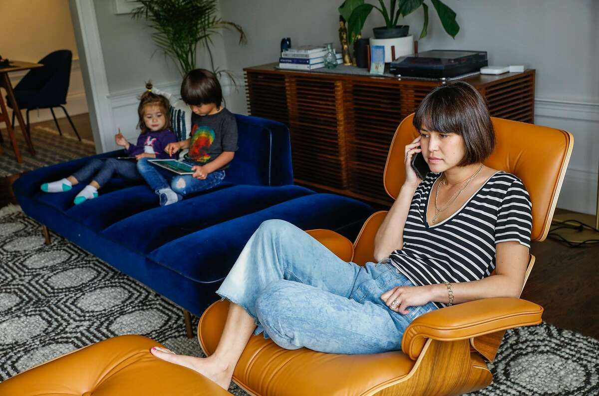 (L-r) Eliette Seeger, 2, and her brother Graham Seeger,4, relax on their iPads while mom Jenny Seeger listens to work voicemails at their home on Thursday, April 16, 2020 in San Francisco, California. Before the shelter in place took effect due the the coronavirus the Seeger�s used to only allow their children 30-minutes of screen time. Now that they are working from home in quarantine they�ve had to extend the use of iPad�s and television to several hours to get their work done.