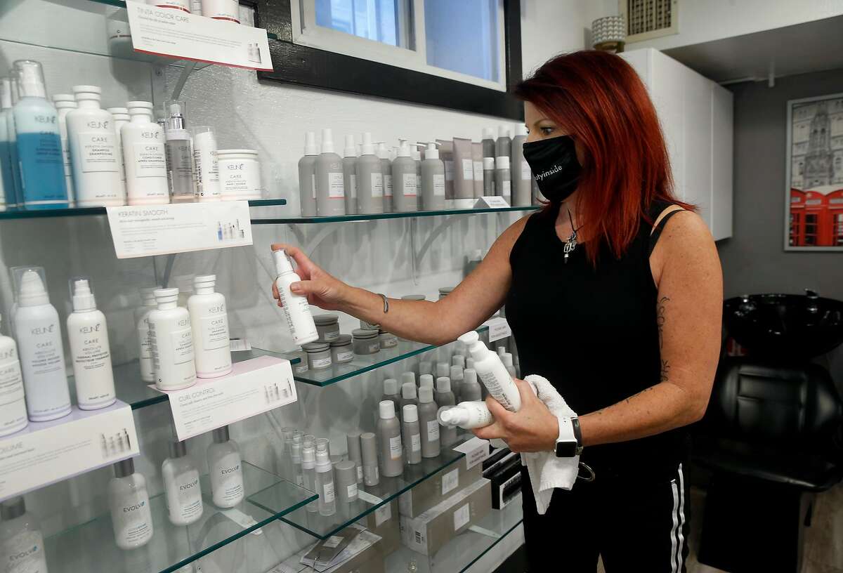 Alicia Orabella stocks shelves of hair care product at her Orabella Hair Studio in Oakland, Calif. on Wednesday, Aug. 26, 2020. Orabella has decided against reopening her small studio when Alameda County loosens restrictions on hair salons Friday allowing them to operate outdoors only.