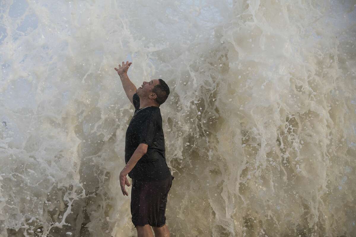 Water falls over Jimmy Villarreal, of Galveston, as a wave hits the seawall while he was watching the surf stirred up by Hurricane Laura Wednesday, Aug. 26, 2020 in Galveston.