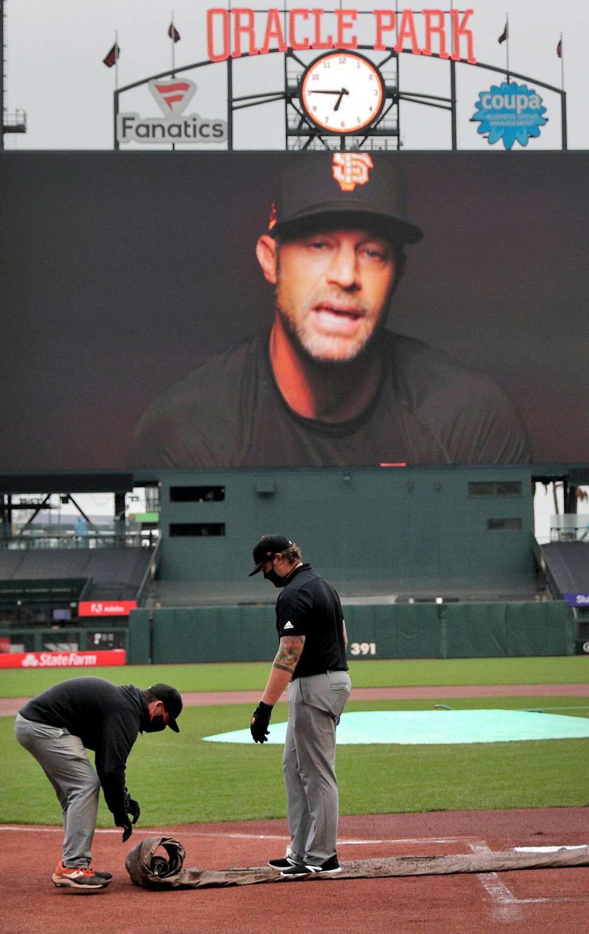 Grounds crews unroll a tarp over homeplate as a message in support if Black Lives Matter featuring manager Gabe Kapler plays on the scoreboard after the game between the San Francisco Giants and the Los Angeles Dodgers was postponed at Oracle Park in San Francisco, Calif., on Wednesday, August 26, 2020.