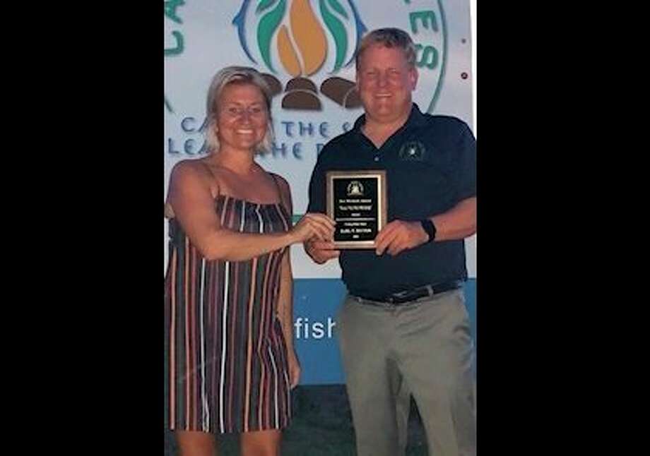 Camp Fish Tales Executive Director Shannon Forshee presents the Keeper of the Fire award to Board Member Karl Ieuter. (Photo provided)
