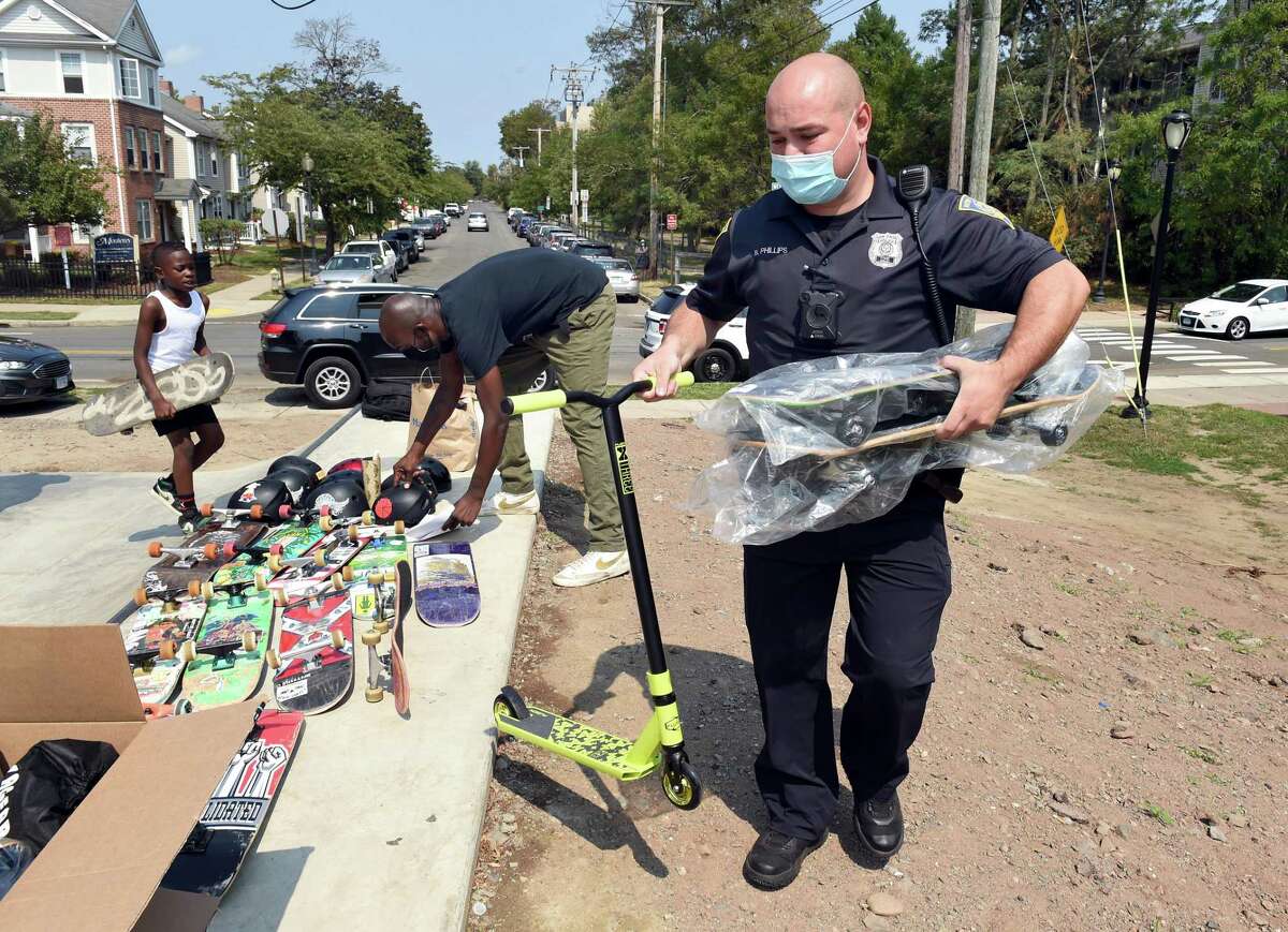 New Haven Police Officer Bryan Phillips brings some of the 5 scooters, 3 skateboards and 8 helmets he purchased to the new Scantlebury Skate Park in New Haven for the ribbon-cutting ceremony Aug. 27, 2020.
