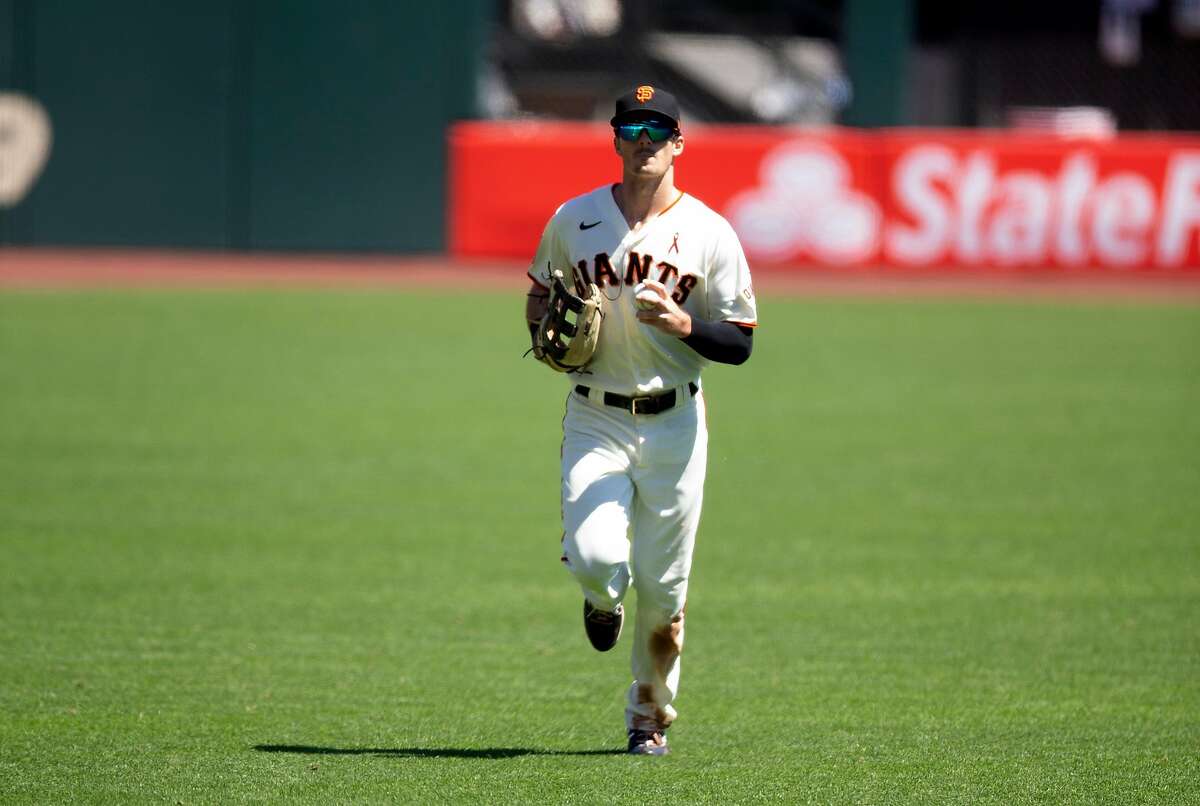 San Francisco Giants center fielder Mike Yastrzemski, left, runs off the field after making the final out of the top of the third inning of a baseball game against the Los Angeles Dodgers on Thursday, Aug. 27, 2020 in San Francisco, Calif.