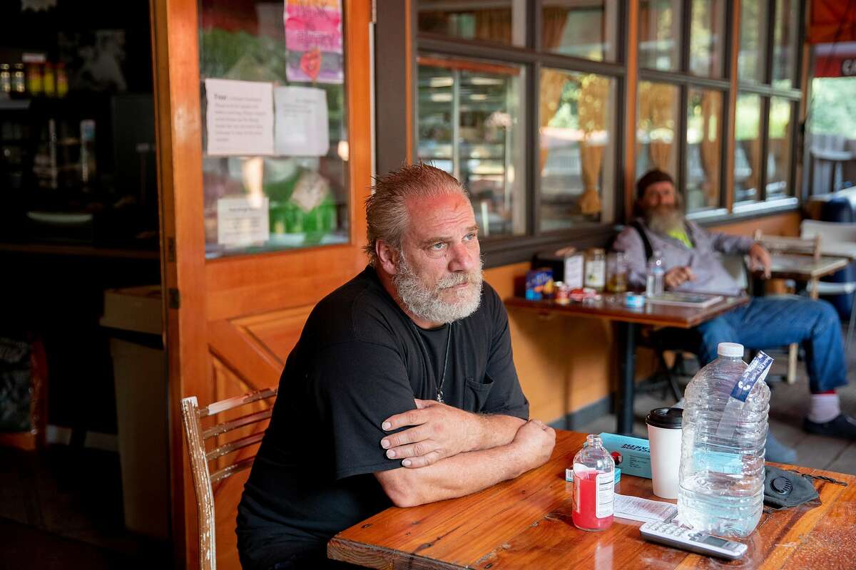 Allen Strong (left) and Brent White of Ben Lomond sit on the porch of La Placa Family Bakery surrounded by emergency food and water while in the evacuation zone of Ben Lomond, Calif. Thursday, August 27, 2020. Ben Lomond residents Strong and White have remained in town, spending the night at the La Placa Family Bakery to keep an eye on it for the Placa family. Residents in the communities of Ben Lomond, Boulder Creek, Last Chance, Swanton and Felton are still under evacuation orders as the CZU Lightning Complex Fire continues to burn in the Santa Cruz Mountains.