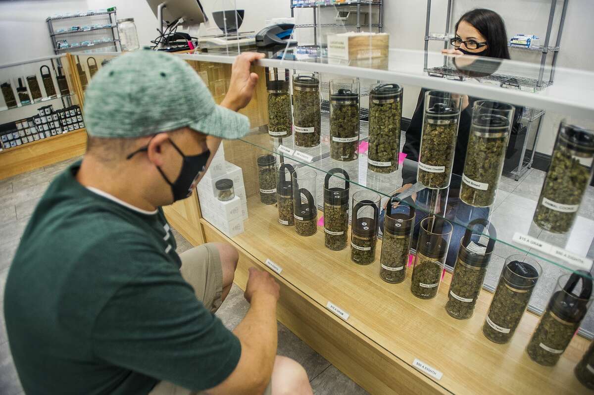 Bobbi Warren, Manager of Nature's Medicines Dispensary, right, assists customer Ryan Rogers, left, as he selects a marijuana strain to purchase Friday, Aug. 28, 2020 inside the business at 3480 E. North Union Rd. in Bay City. (Katy Kildee/kkildee@mdn.net)