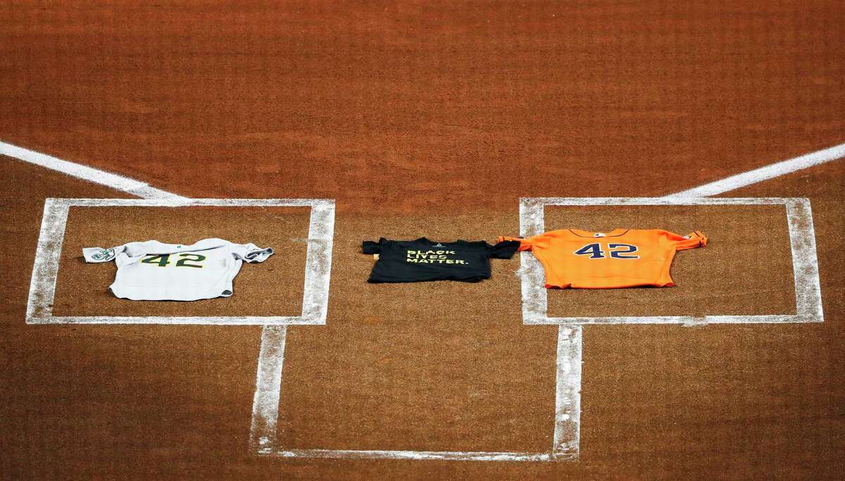 An Oakland Athletics jersey, laid by Marcus Semien, and a Houston Astros jersey, laid by Martin Maldonado, both bearing the No. 42 in honor of Jackie Robinson, flank a Black Lives Matter T-shirt covering home plate Friday in Houston. The teams took the field, observed a moment of silence, and then walked off the field in protest of racial injustice.