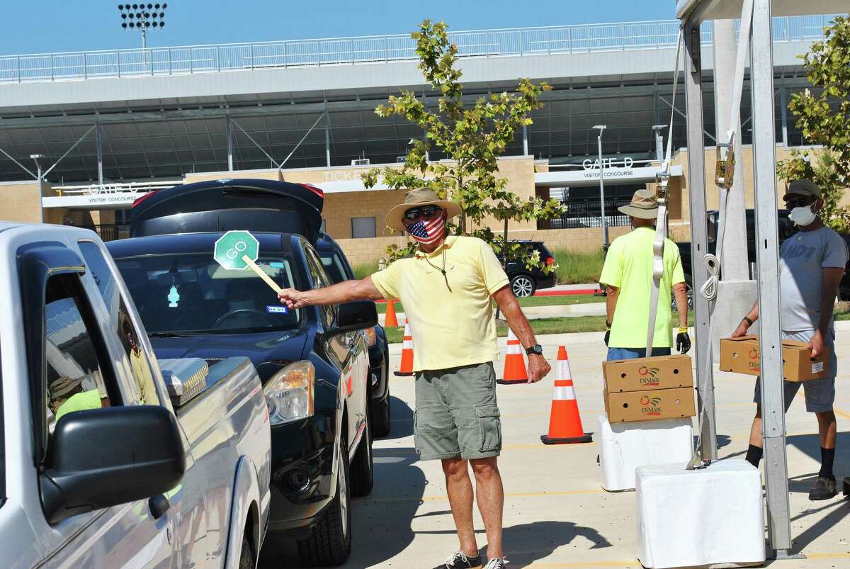 A volunteer directs traffic at Planet Ford Stadium in Spring at the Super Food Site distribution recently for families needing food assistance.
