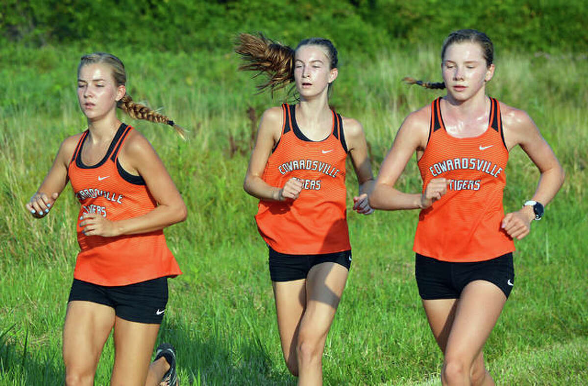 Edwardsville’s Makenna Lueking, left, Maya Lueking, middle, and Riley Knoyle run during the first mile of Saturday’s season-opening dual meet against East St. Louis at Frank Holten State Park.