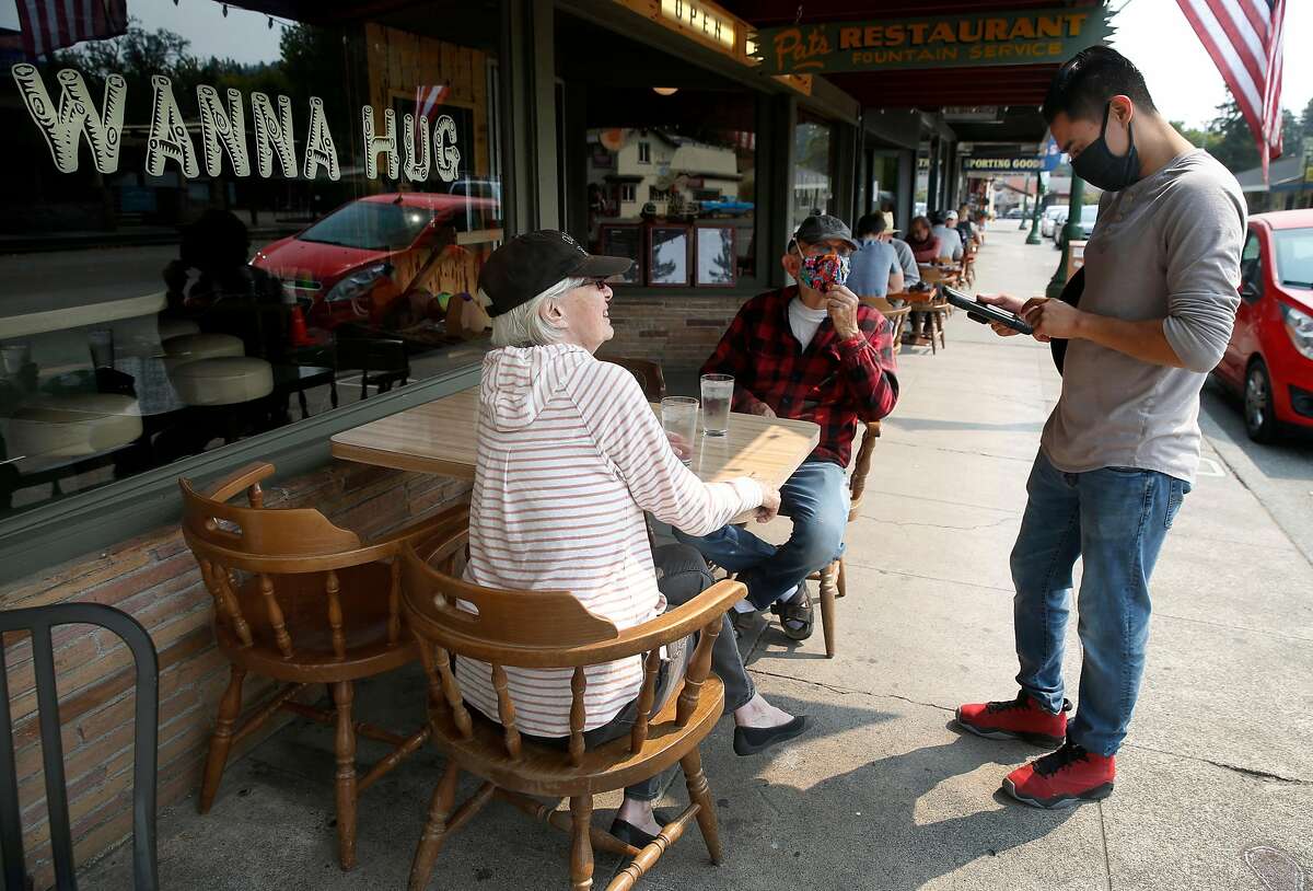 Alexis Guzman (right) takes a breakfast order from Scott and Darlene Kersnar outside Pat's Restaurant in Guerneville, Calif. on Saturday, Aug. 29, 2020. The Kersnars were able to return to their home Friday after they were forced to evacuate early last week. The town on the Russian River is gradually reopening after evacuation orders were lifted from the LNU Lightning Complex fires.