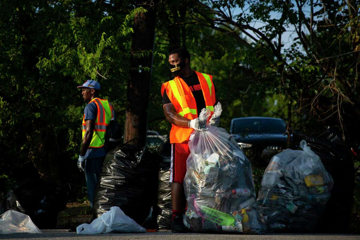 Volunteer Charles Cooper ties up a large bag of trash during a community clean up in the Third Ward of Houston on Sunday, Aug. 30, 2020. Cooper is a part of The REUP Movement, a non-profit dedicated to helping the disadvantaged and mentoring youth in Houston.