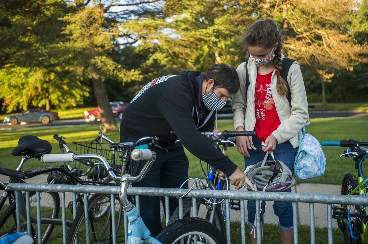 Dan Goodell, center, helps his daughter Grace, 11, right, lock up her bike before the first day of school at Jefferson Middle School Monday, Aug. 31, 2020. (Katy Kildee/kkildee@mdn.net)