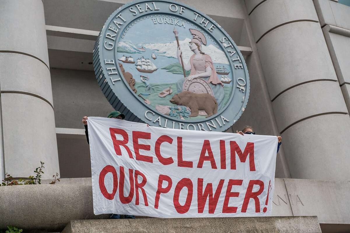 People hold banners as they protest against a PG&E bailout in San Francisco, Calif. on Wednesday, May 20, 2020.