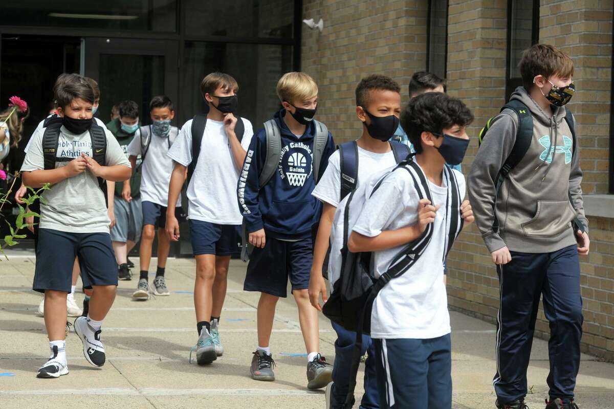 Students leave school after the first day of classes at Holy Trinity Catholic Academy, in Shelton, Conn. Aug. 31, 2020.