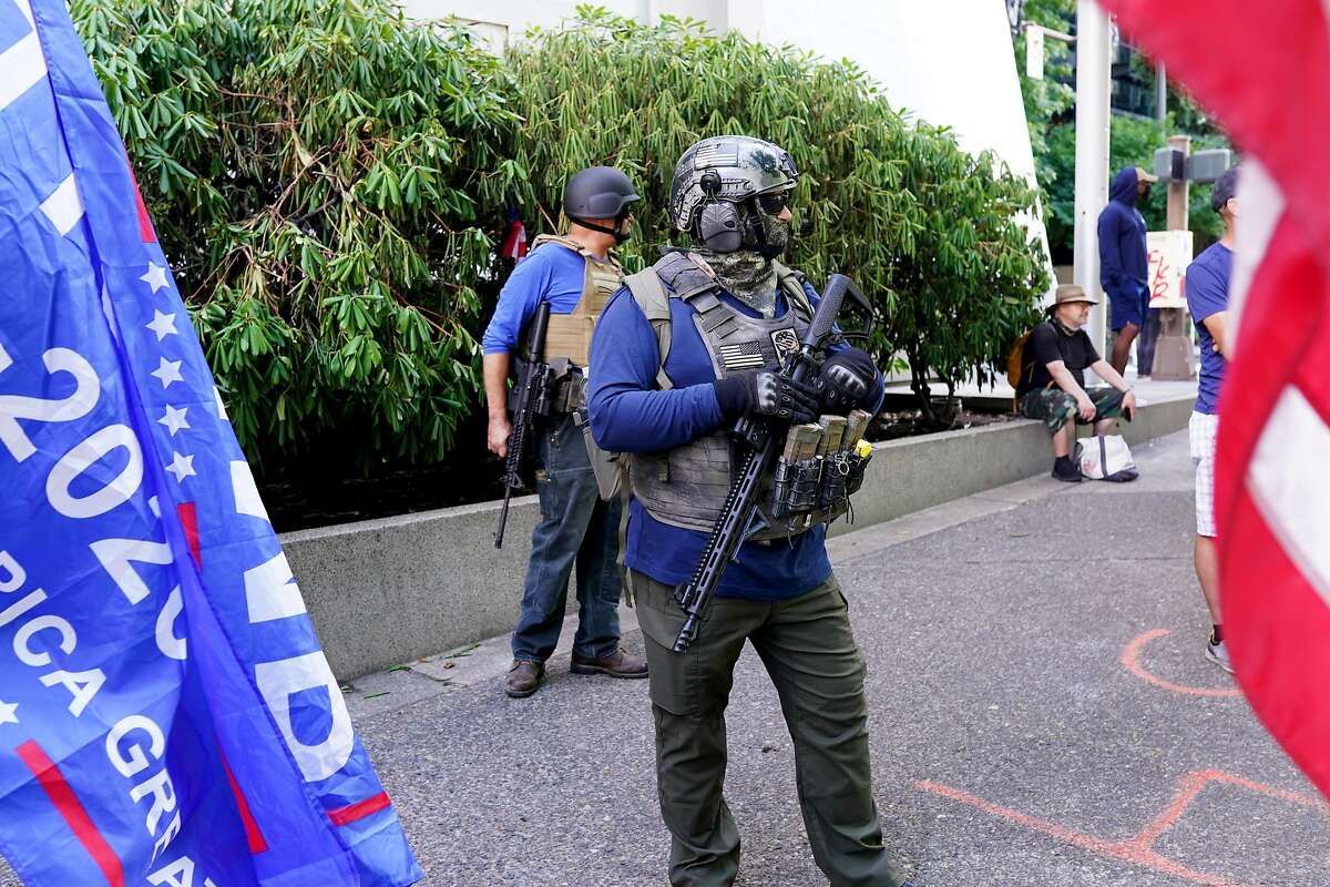 PORTLAND, OR - AUGUST 22: Right wing protesters with assault rifles look on during a rally in front of the Multnomah County Justice Center that drew anti-police counter protesters on August 22, 2020 in Portland, Oregon. For the second Saturday in a row, right wing groups gathered in downtown Portland, sparking counter protests and violence. (Photo by Nathan Howard/Getty Images)