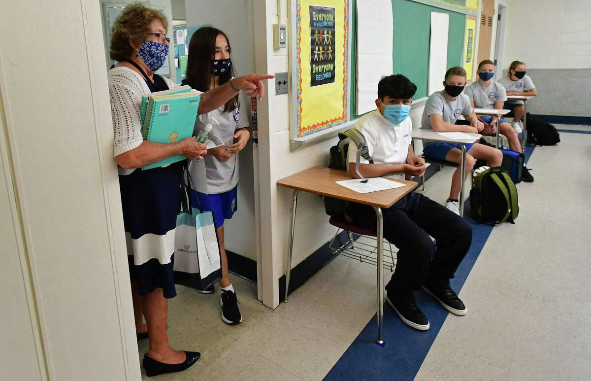 All Saints Catholic School eighth-grade teacher Patricia Hauptman greets her students as they attend their first day of class, Tuesday, September 1, 2020, in Norwalk, Conn. The school staggered its opening this year with grades six through eight attending Tuesday.