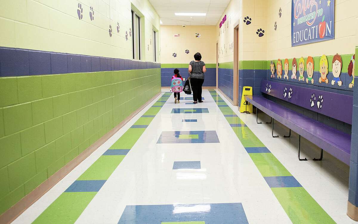M.S. Ryan Elementary School paraprofessional Araceli Arredondo, right, escorts a student down a normally busy hall towards the cafeteria on Aug. 24 during the first day back to school for some students during the COVID-19 pandemic.