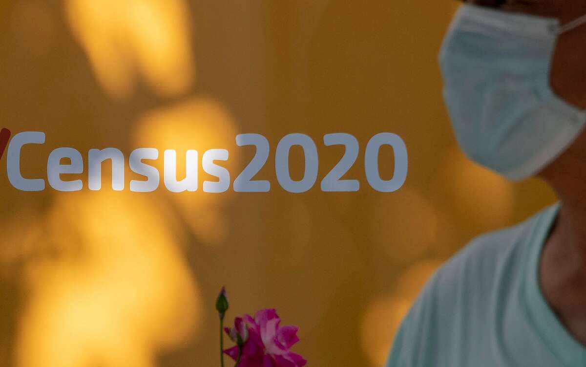 A man in a face mask walks past a sign in Los Angeles encouraging participation in the 2020 census.