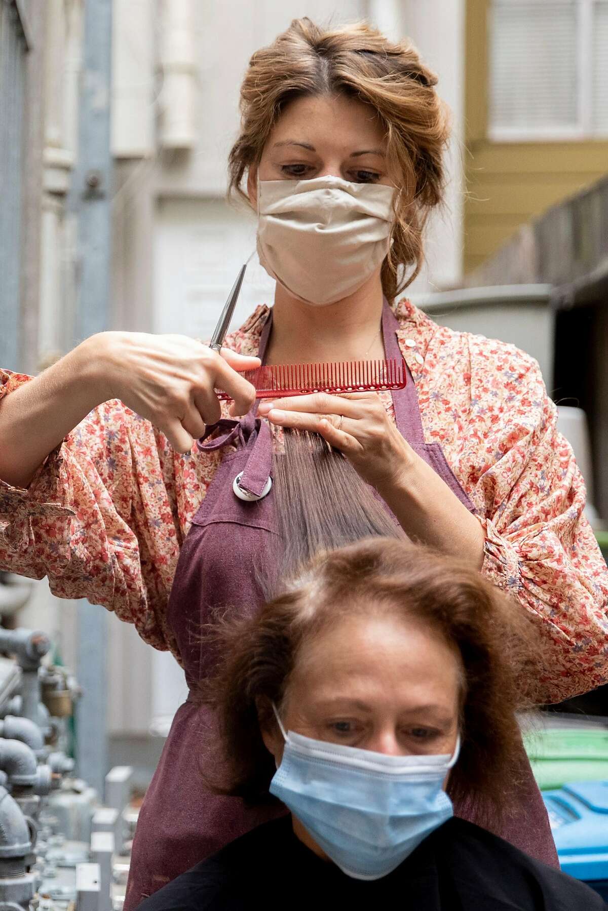 Plum Organic Beauty owner Danica Winters cut Martha Gregg's hair in the outdoor patio of her salon in San Francisco, Calif. Tuesday, September 1, 2020. Massage, hair and nail salons in San Francisco are permitted to open outdoors starting Tuesday, September 1 for the first time since COVID-19 shelter-in-place orders shuttered most personal service businesses.