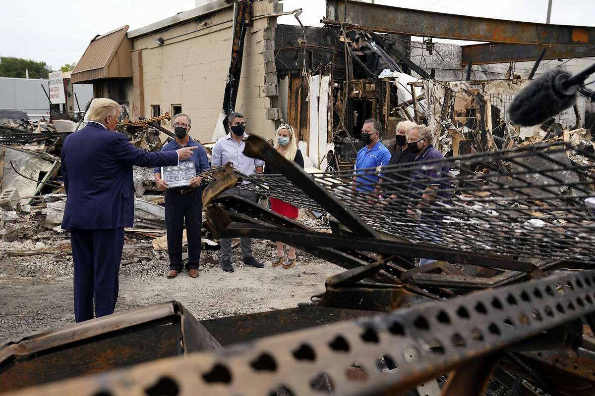 President Donald Trump talks to business owners Tuesday, Sept. 1, 2020, as he tours an area damaged during demonstrations after a police officer shot Jacob Blake in Kenosha, Wis. (AP Photo/Evan Vucci)