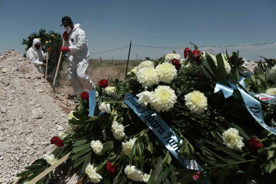 Workers in full protection gear against the spread of the new coronavirus bury a coffin in an area of the San Rafael municipal cemetery that has been set apart for COVID-19 cases in Ciudad Juárez, Mexico. Labor activists believe that the working conditions are contributing to a rising mortality rate among factory workers in Mexico. Photo: Christian Chavez /Associated Press / Copyright 2020 The Associated Press. All rights reserved