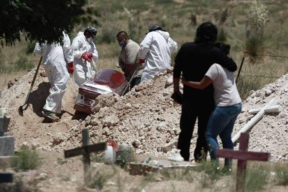 Family members mourn as workers wearing protection gear against the spread of the coronavirus bury their loved one in an area of the cemetery set apart for COVID-19 cases, in Ciudad Juárez, Mexico. Photo: Christian Chavez /Associated Press / Copyright 2020 The Associated Press. All rights reserved