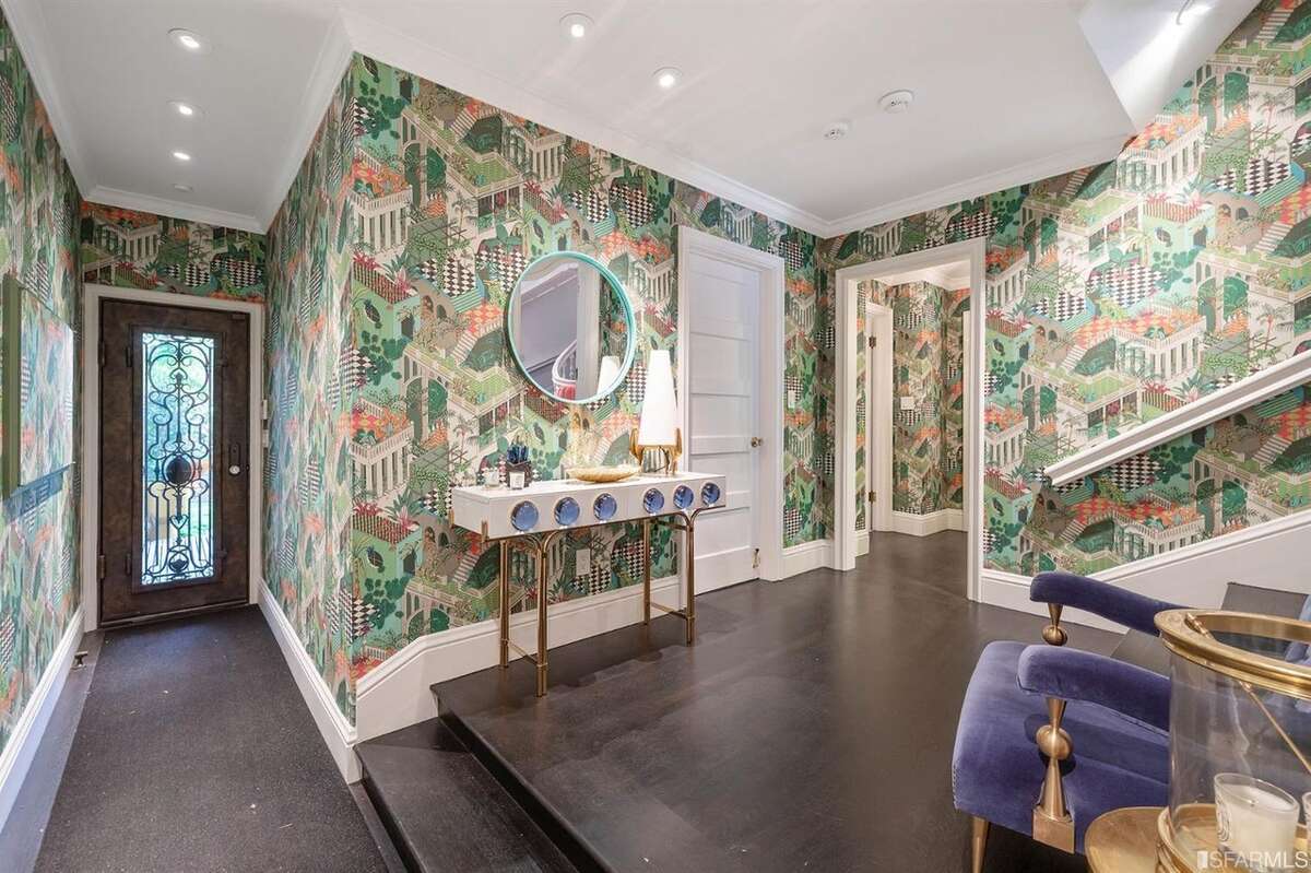 The juxtaposition between the classic exterior and whimsical Adler-designed interior has brought the home a lot of interest. "1230 Sacramento has drawn more attention from media outlets than any other listings that I have had," said listing agent MaryLou Castellanos. "Many agents have reached out and I have more positive comments on my Facebook page than I can count." One Adler touch: this wallpaper was designed to bring the feel of the backyard into the garden-level area of the home, located a few stairs down and just behind the more grand foyer in the picture above. 