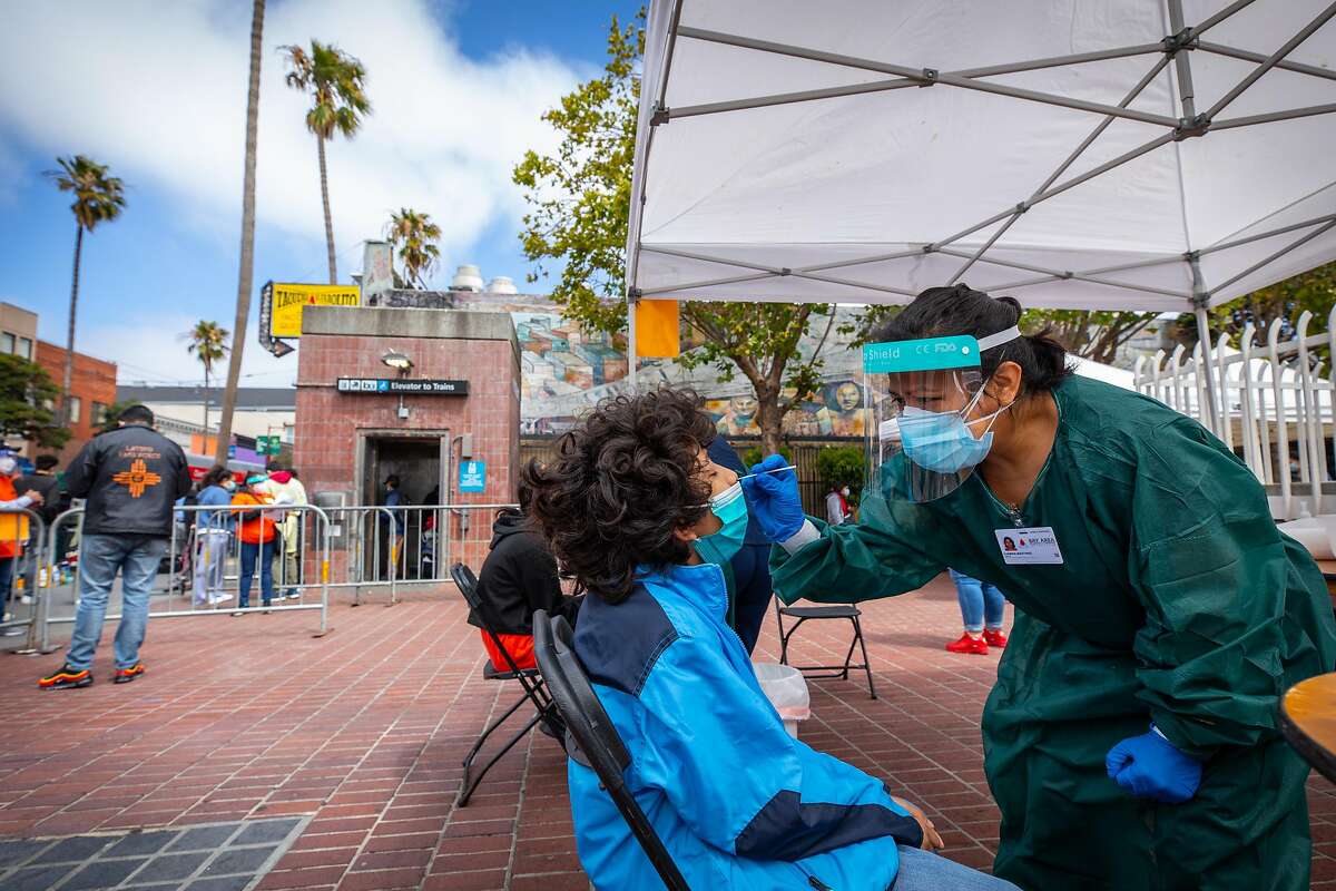 Carmen Martinez, right, gives a COVID-19 test to Daniel Hernandez, 9, at a COVID-19 testing area that was set up at the 24th Street Mission Station by BART and UCSF on Wednesday, Aug. 5, 2020. The testing program aims to help get more members of the Latino community tested.