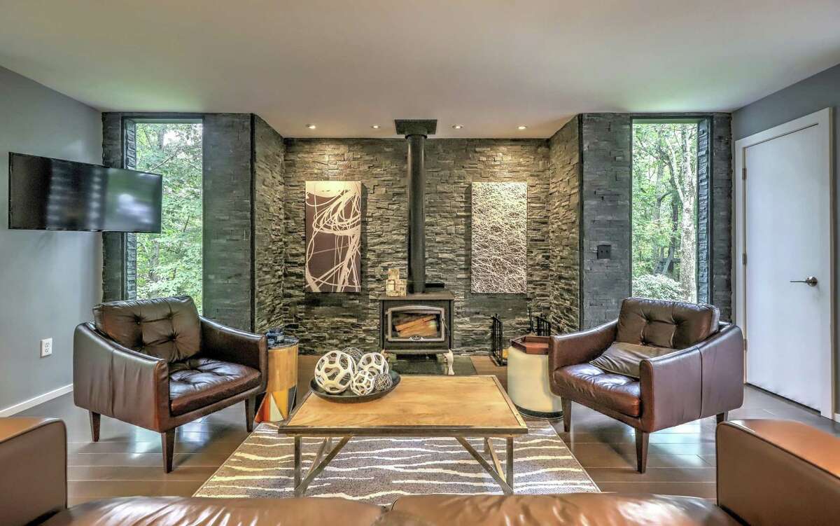 In the living room there is a wall of stone that houses a wood-burning stove and sliding doors to a balcony/deck. A second set of sliding doors lead to the larger deck. On the full finished walk-out lower level there is a flexible room, which could be used as a second family room, a game or recreation room or a media space. It has a propane stove, bamboo flooring, and sliding doors to the patio. Like the family room, one of the two bedrooms on this level has a wood paneled wall and a door to the patio. The full bath features a trough-style sink.