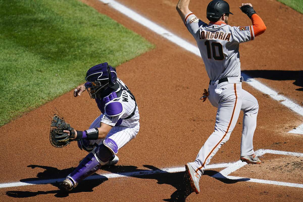 Colorado Rockies catcher Tony Wolters, left, fields the throw as San Francisco Giants' Evan Longoria scores on a single hit by Alex Dickerson in the first inning of a baseball game Wednesday, Sept. 2, 2020, in Denver. (AP Photo/David Zalubowski)