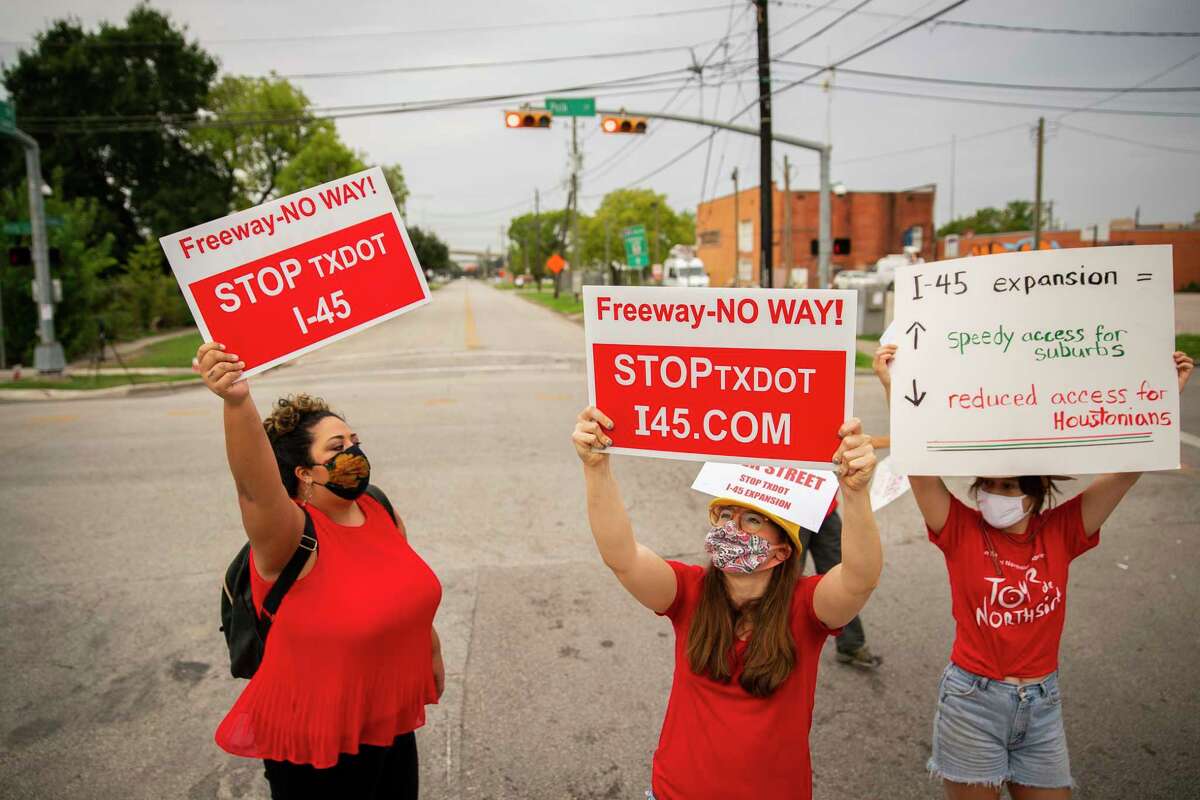 Desiree Alejandro, left, and Danielle Sullivan, center, hold up signs in the middle of the street during a demonstration at the intersection of Polk and St. Emanuel east of downtown Houston on Sept. 3, 2020. The Texas Department of Transportation’s plans to rebuild Interstate 45 between downtown and Greenspoint would close Polk Street along with negatively impacting communities north of downtown, critics say.