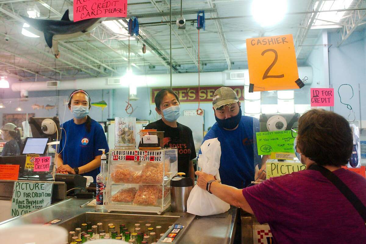 Debbie Duong, left and Steve Nguyen, right, serve customers as store manager Samantha Tran, center, chats with customer Jan Larsen at Rose's Seafood market in Seabrook.