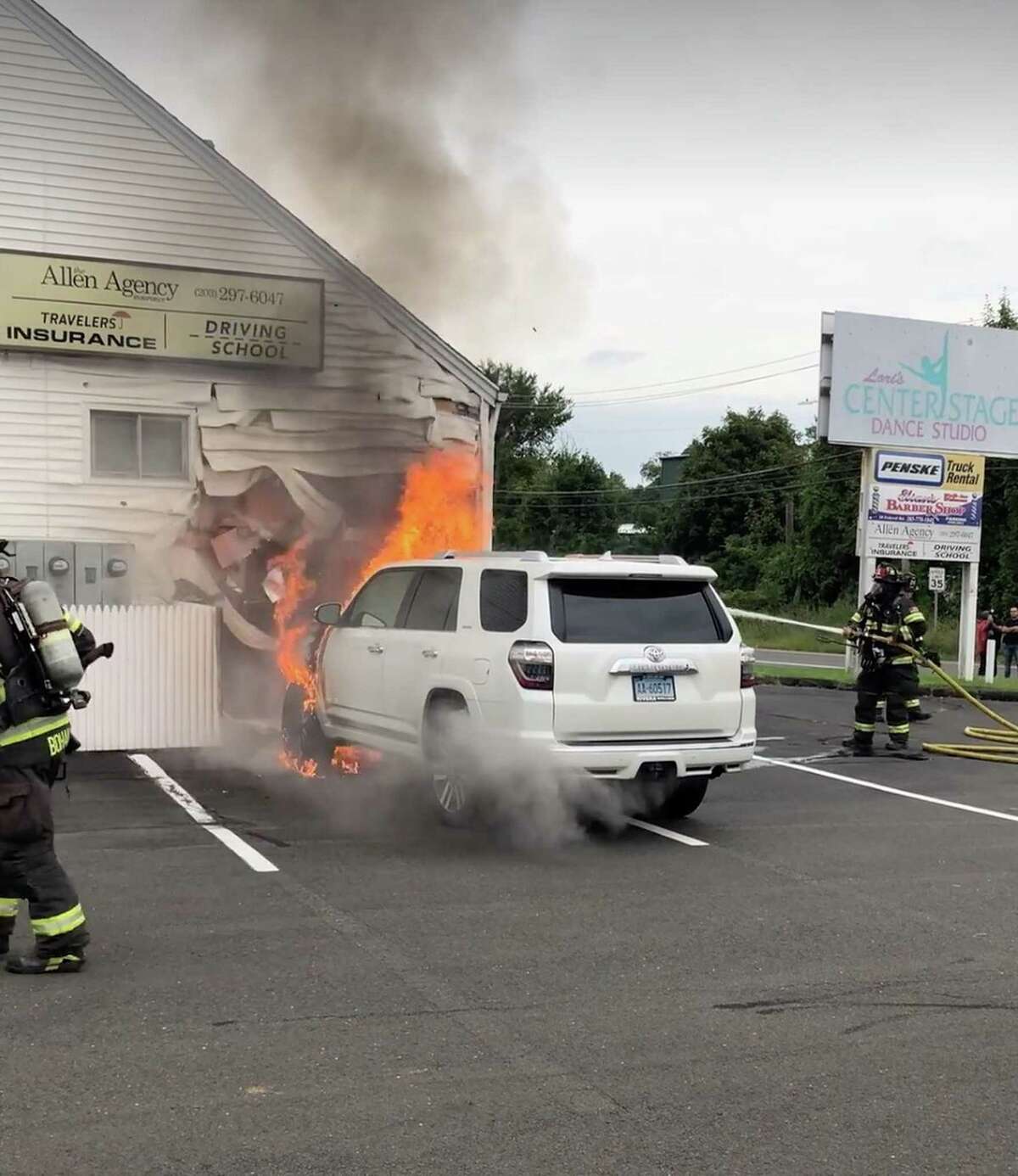 Firefighters extinguish an SUV after it caught fire in close proximity to a building on Federal Road in Danbury, Conn., Sept. 2, 2020.