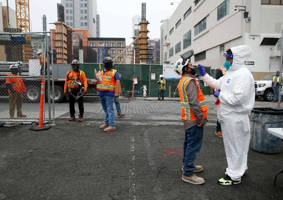 Armando Vidrio (right) collects a sample from a construction worker during weekly on-site coronavirus testing for Build Group employees and workers constructing a 302-unit residential building at 434 Minna Street in San Francisco, Calif. on Thursday, Sept. 3, 2020.