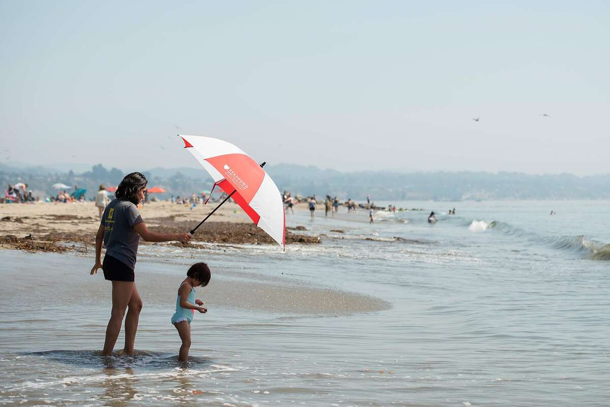 Marlene Hernandez shields 5-year-old Teresa Buenrostro from the sun with an umbrella at Capitola Beach on Sept. 4, 2020