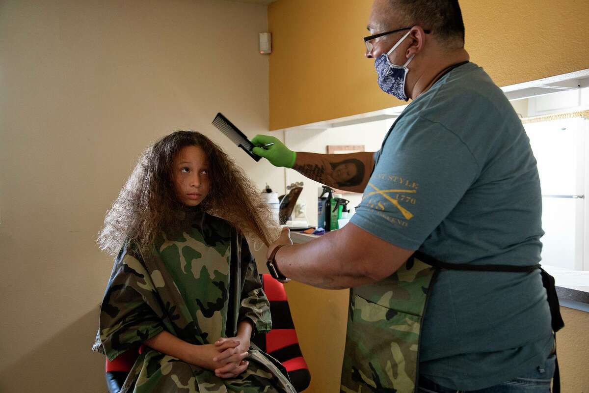Abigail Sizenbach, 10, gets her hair cut by Juan Rodriguez at Avistar at the Oaks apartments in San Antonio on Thursday, Sept. 3, 2020. Rodriguez is a resident there who lost his job working in an oil field in February due to COVID-19. Sizenbach lives in another Avistar apartment complex nearby.