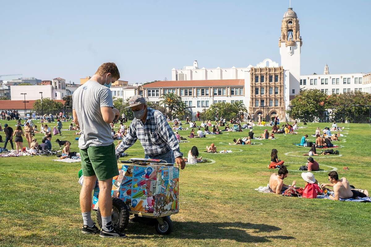 An ice cream vendor as people gather in the physical distancing circles during the Labor Day weekend at Dolores Park, Saturday, Sept. 5, 2020, in San Francisco, Calif.