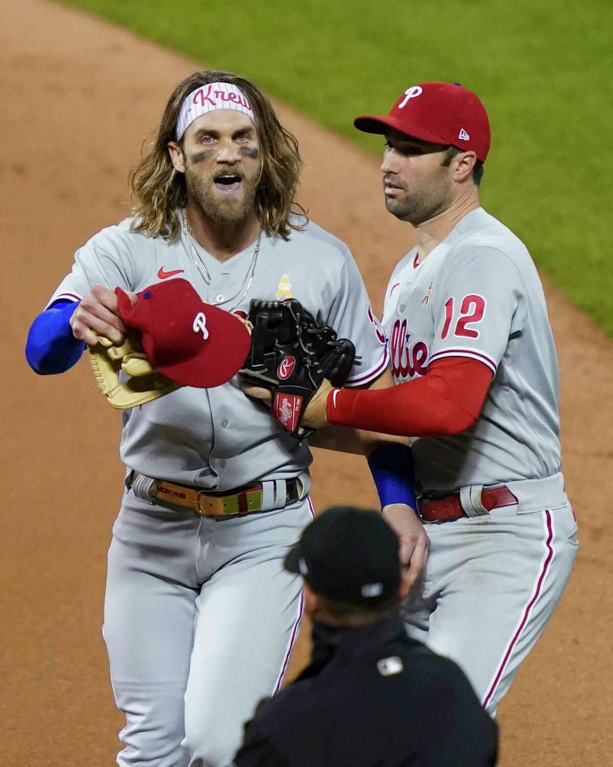Philadelphia Phillies' Bryce Harper, left, reacts next to Neil Walker (12) after umpire Roberto Ortiz, below, threw him out of the team's baseball game against the New York Mets during the fifth inning Saturday, Sept. 5, 2020, in New York. (AP Photo/John Minchillo)