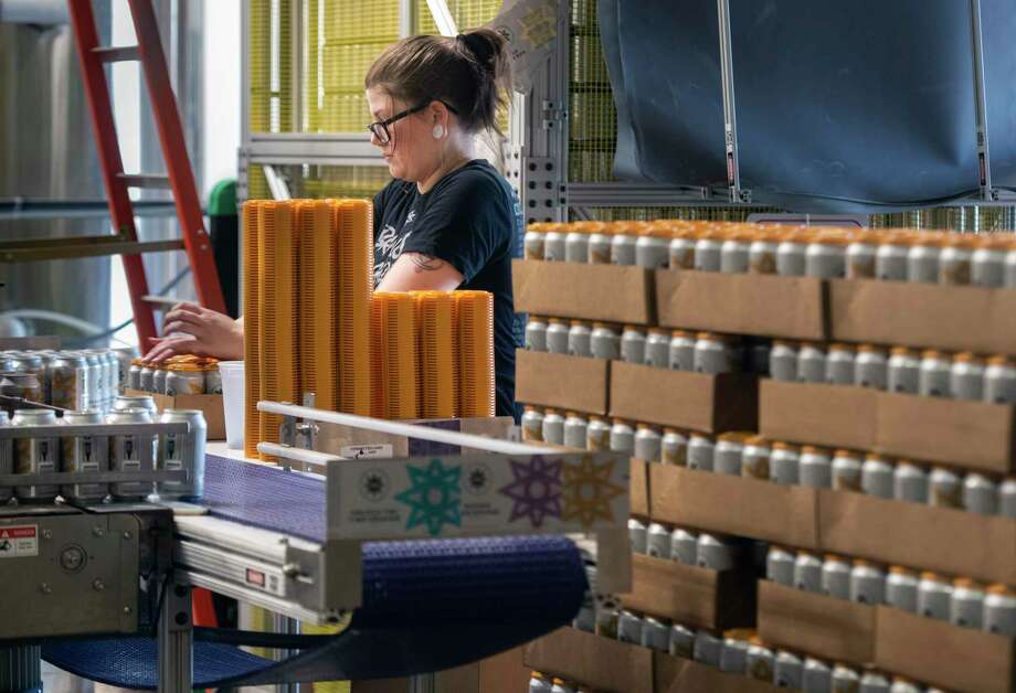 Brittany Zaborniak, a server at Cosmic Eye Brewing, stacks a tower of beers on the canning operation line, Friday, Aug. 21, 2020, in Lincoln, Neb. The Brewers Association warned at the end of July that aluminum can manufacturers were at capacity with no way to increase production this year. (Justin Wan/Lincoln Journal Star via AP) Photo: Justin Wan, MBI / Associated Press / LINCOLN JOURNAL STAR