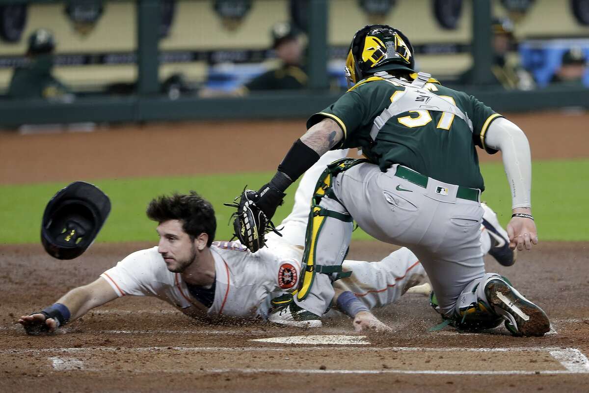 Houston Astros' Kyle Tucker, left, is tagged out at the plate by Oakland Athletics catcher Jonah Heim during the first inning of the second baseball game of a doubleheader Saturday, Aug. 29, 2020, in Houston. (AP Photo/Michael Wyke)