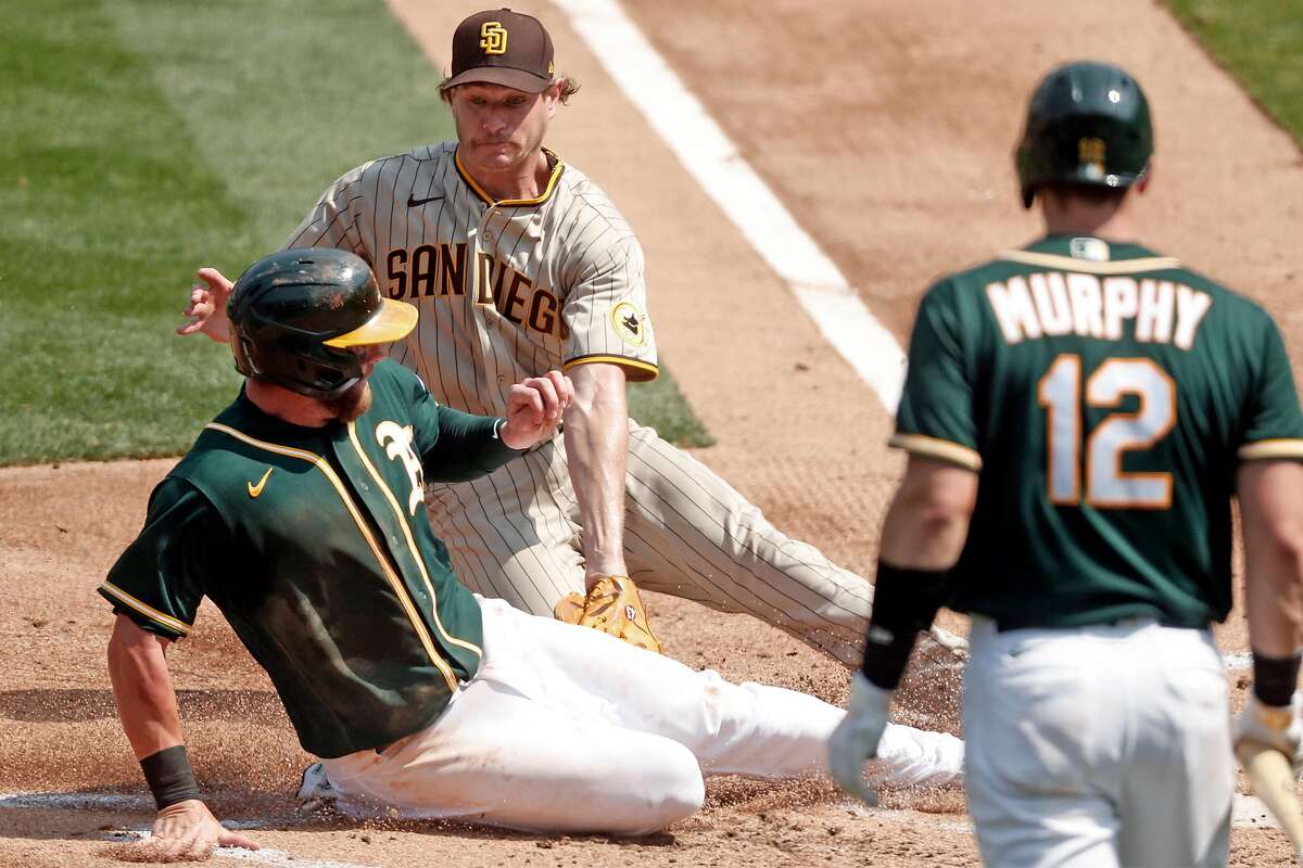 Oakland Athletics' Robbie Grossman is tagged out at home plate by San Diego Padres' Garrett Richards while trying to score on dropped third strike against Sean Murphy in 2nd inning during MLB game at Oakland Coliseum in Oakland, Calif., on Sunday, September 6, 2020.