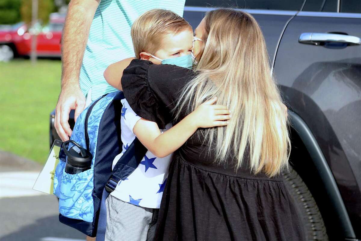 A tearful Kellin Frost hugs her son Hudson, 4, who is beginning his first day of kindergarten at Miller-Driscoll on Sept. 8, 2020, in Wilton, Conn. Students, meanwhile - wearing masks, determined countenances, and toting their backpacks - exchanged greetings with the bevvy of staff and strolled comfortably to their selected spot to be introduced - or re-introduced - to their school.