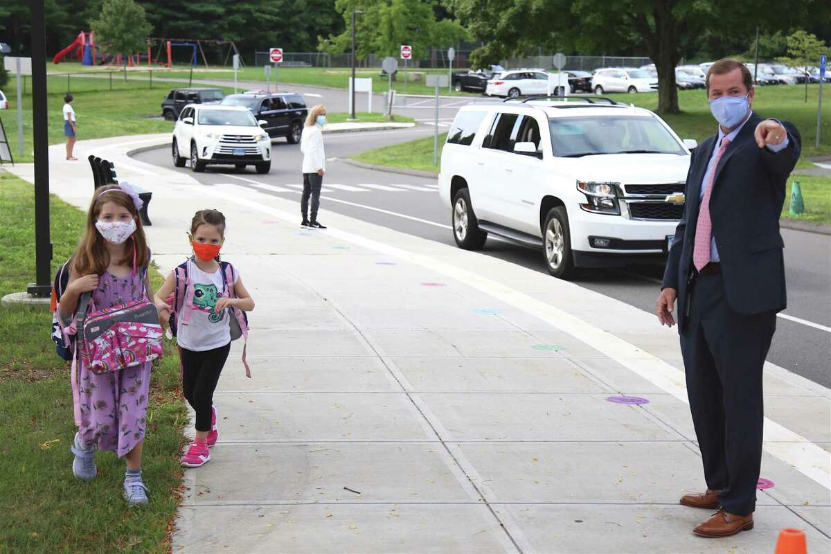 Superintendent of School Kevin Smith directs two students into school for their first day of in-person class at Miller-Driscoll on Sept. 8, 2020, in Wilton, Conn.