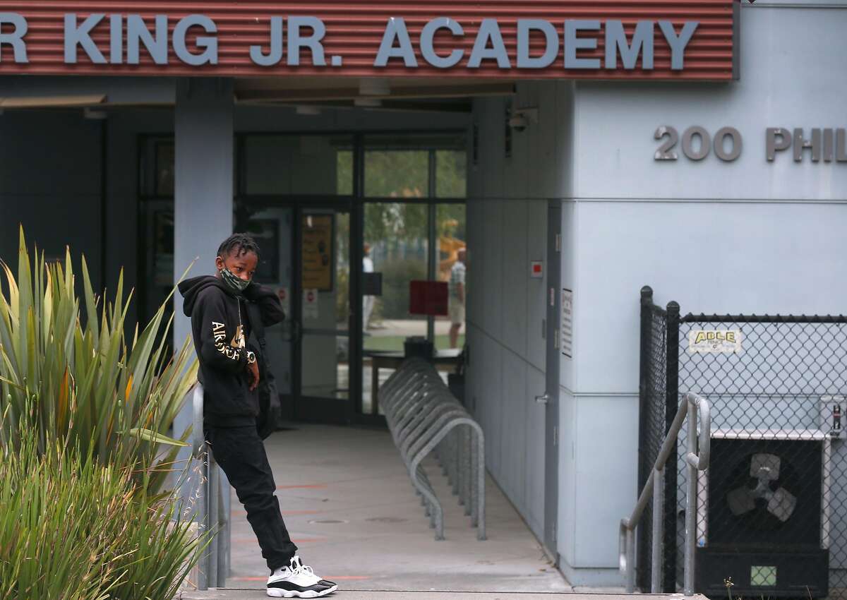 Omar Williams, a 7th grader at Bayside Martin Luther King Jr. Academy, waits to pick up a laptop to begin the school year with online teaching in Sausalito, Calif. on Tuesday, Sept. 8, 2020. The K-8 school was anticipating opening to in-class learning Tuesday but a potential positive test of the COVID-19 virus of a staff member delayed the opening for at least one week.
