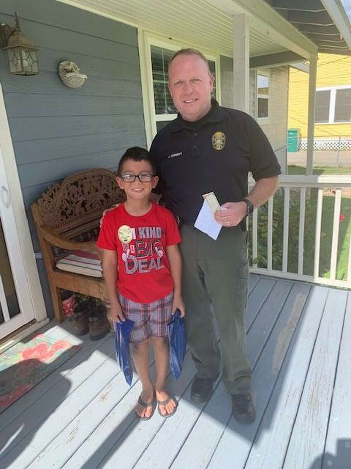 David Jimenez and Conroe Police Chief Jeff Christy pose for a Aug. 27 picture outside the 7-year-old's home in Conroe. The second grader wrote a letter sending police thanks for their work.