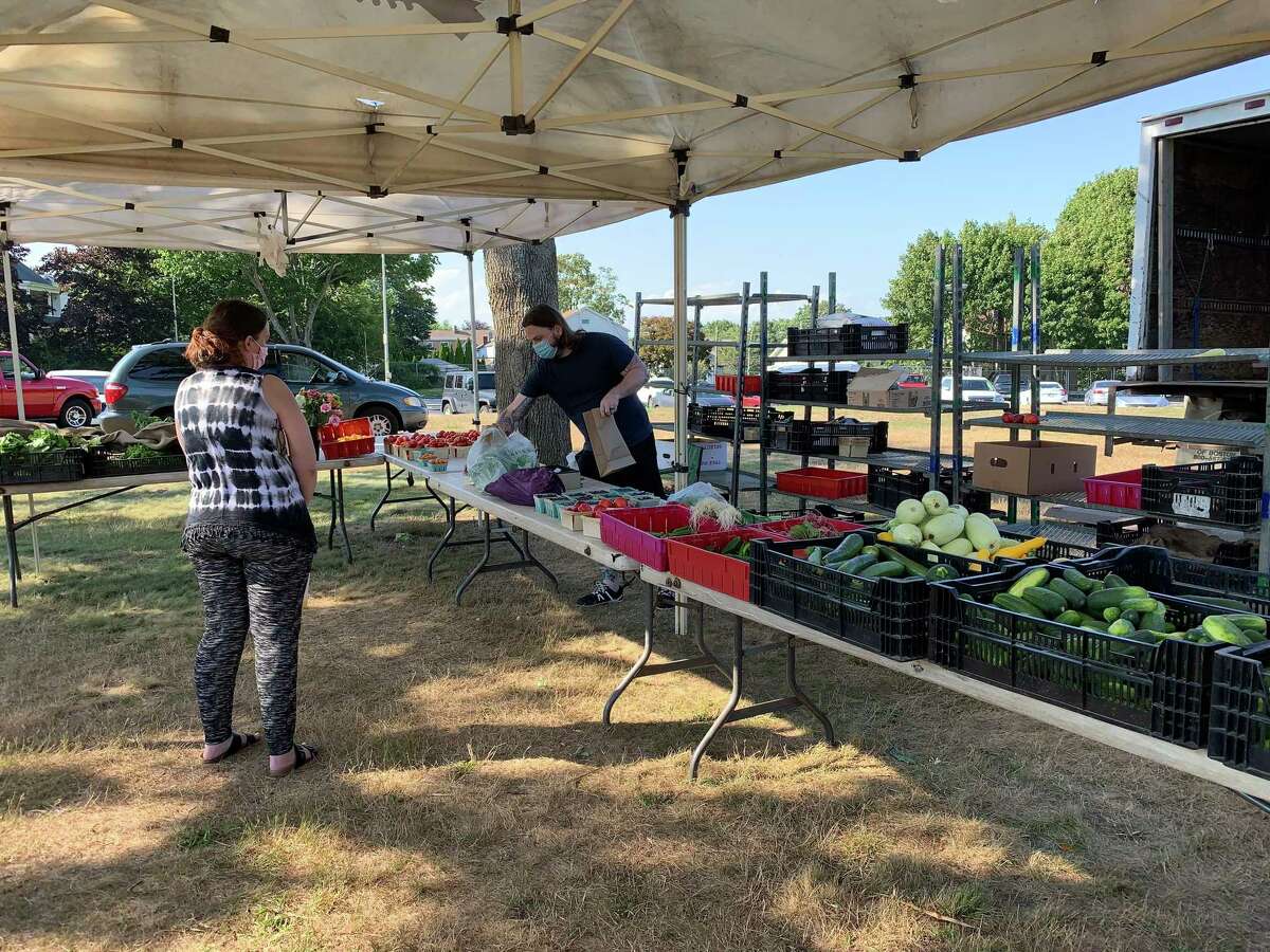 Cole Riemer (in the black T-shirt behind the table) staffed the Niantic-based Smith’s Acres table at the Aug. 5 Field of Greens Farmers Market in New London. The market, like many in the region, aims to make fresh produce accessible to city neighborhoods, and it honors federal food assistance benefits.