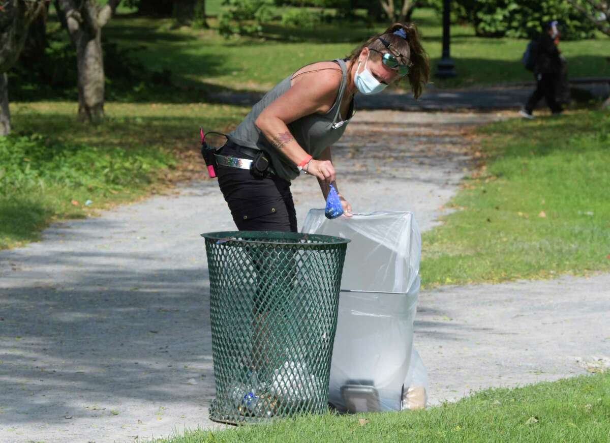 A crew member of the television show Modern Love places garbage into a garbage receptacle that will be seen in the shot as preparation to film a scene at Washington Park on Wednesday, Sept. 9, 2020, in Albany, N.Y. (Paul Buckowski/Times Union)